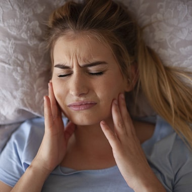 A women lying down suffering from TMJ symptoms