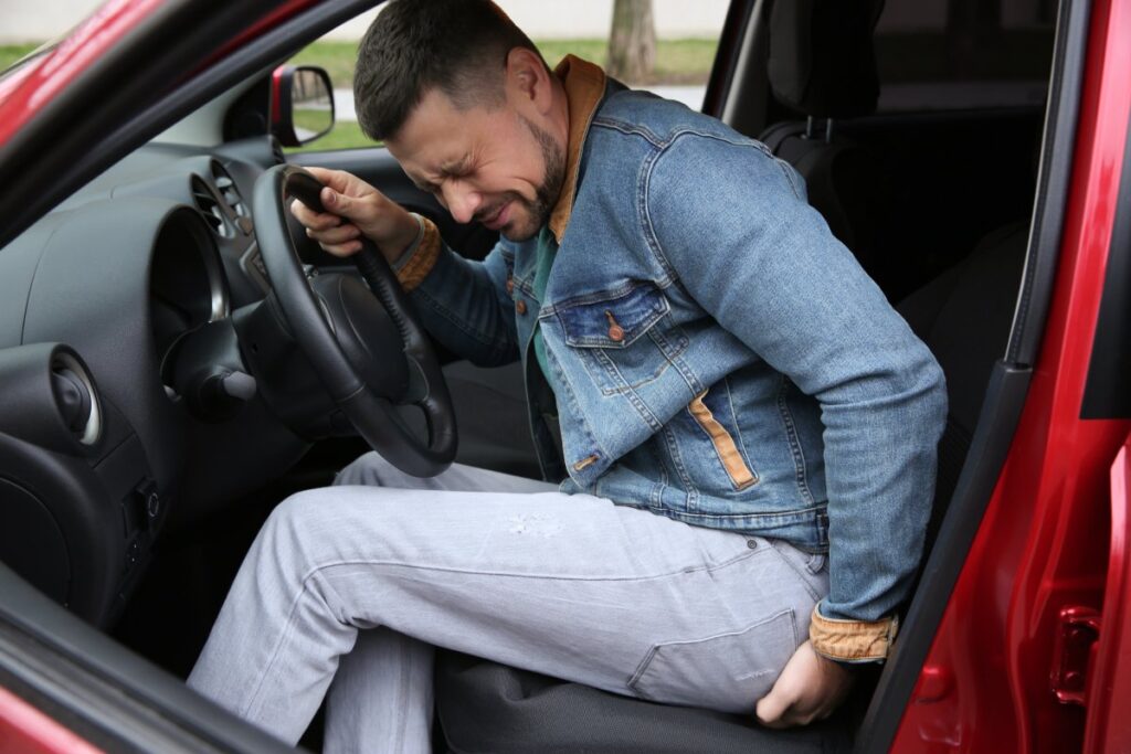 man suffering from back pain in car