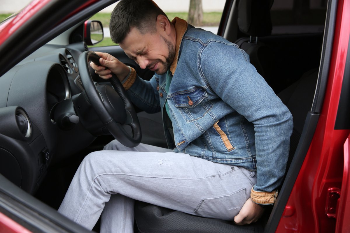 man suffering from back pain in car